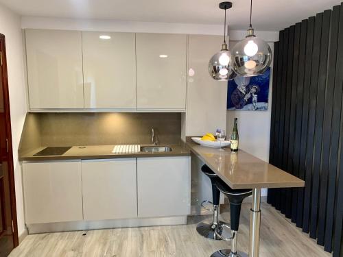 een keuken met witte kasten en een tafel met een wastafel bij Apartamento Tahoro in La Orotava