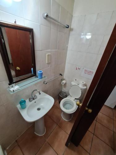 
a bathroom with a toilet, sink, and mirror at Metropole Hotel in Limassol

