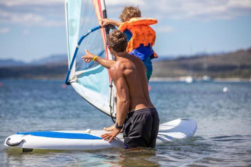 a man holding a child on a wind sail on the beach at Hotel Club Saraceno - Bovis Hotels in Àrbatax