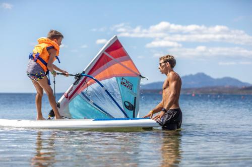 a man and a girl on a surfboard with a sail at Hotel Club Saraceno - Bovis Hotels in Àrbatax