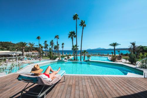 a woman laying on a chair next to a swimming pool at Hotel Club Saraceno - Bovis Hotels in Àrbatax
