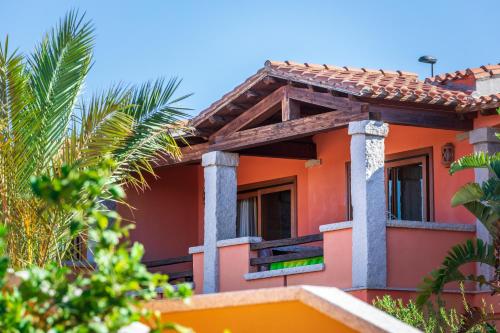 an orange house with columns and palm trees at Hotel Club Saraceno - Bovis Hotels in Àrbatax