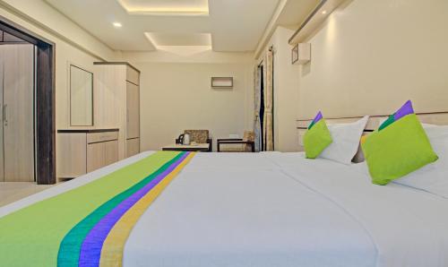a bedroom with a large white bed with rainbow pillows at Treebo Sumati Baner in Pune