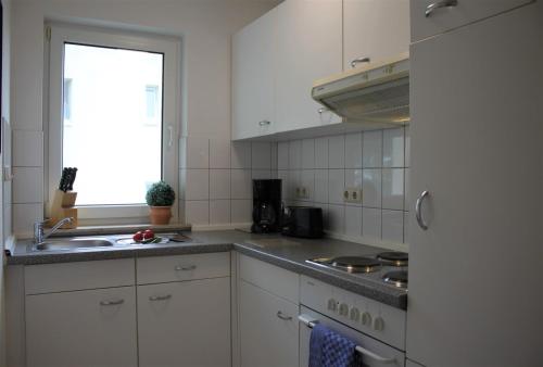 d'une cuisine avec des placards blancs, un évier et une fenêtre. dans l'établissement Seute Deern, à Kirchdorf