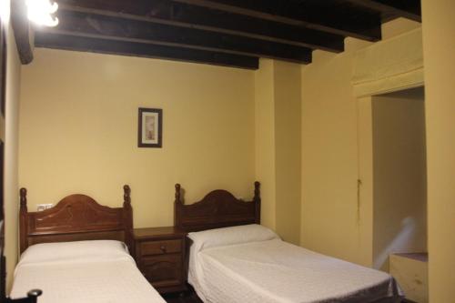 two beds in a room with yellow walls at Casa Rural la Cancha I in Navalacruz