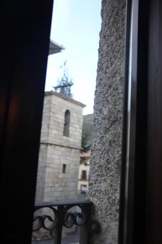 a view of a clock tower from a window at Casa Rural la Cancha I in Navalacruz