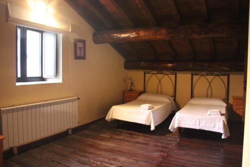 two beds in a room with a window at Casa Rural la Cancha II in Navalacruz