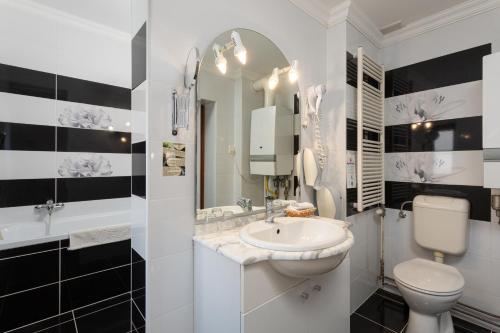 a white bathroom with a sink and a toilet at Illés Hotel in Szeged