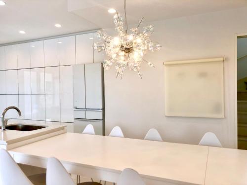 a kitchen with a white table and a chandelier at HOKULANI by the sea オーシャンビューのプール付き貸別荘 in Isumi