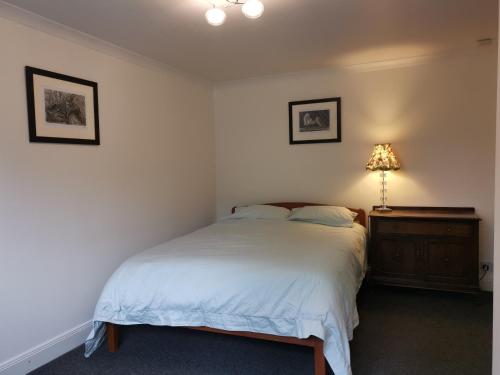 a bedroom with a bed and a lamp on a dresser at Relax in a 1 Bedroom Apartment near a country Pub in Eyemouth