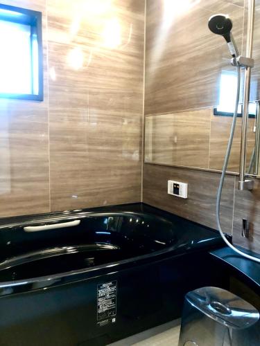 a bath tub in a bathroom with a shower at HOKULANI by the sea オーシャンビューのプール付き貸別荘 in Isumi