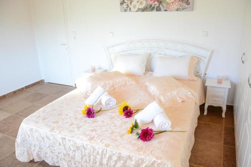 a bedroom with a white bed with flowers on it at Villa Vicky Corfu in Agios Ioannis