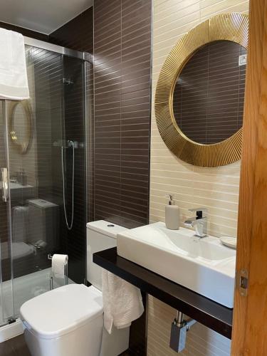 a bathroom with a sink and a toilet and a mirror at Mirador Islas de Arousa in Ribeira