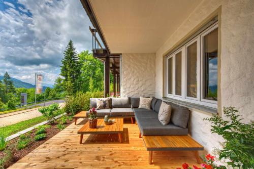 eine Terrasse mit einem Sofa, Tischen und einem Fenster in der Unterkunft Allgäuer Panoramahotel in Oberstaufen