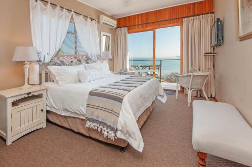 a bedroom with a bed and a view of the ocean at 18 On Kloof Guest House in Gordonʼs Bay