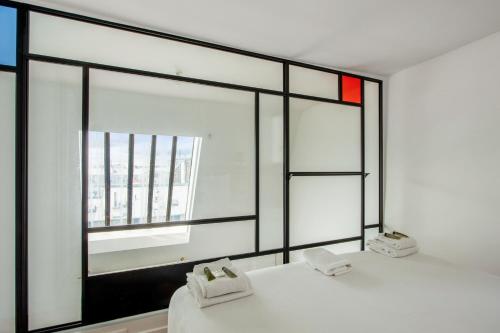 - une chambre dotée d'une grande fenêtre avec des draps blancs dans l'établissement Studio Emerald - Welkeys, à Paris