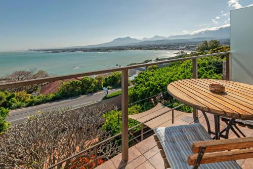 a balcony with a table and chairs and a view of the ocean at 18 On Kloof Guest House in Gordonʼs Bay