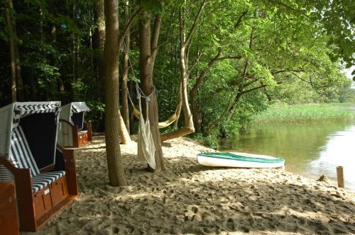 a hammock and a boat on the shore of a river at Seehotel Frankenhorst - BW Signature Collection in Schwerin