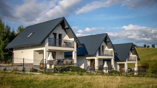 a white house with a black roof at OSADA Rokicie in Kluszkowce