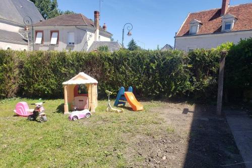 une cour avec des équipements de jeux pour enfants dans l'herbe dans l'établissement Maison chaleureuse avec parking gratuit sur place, à Saint-Romain-sur-Cher