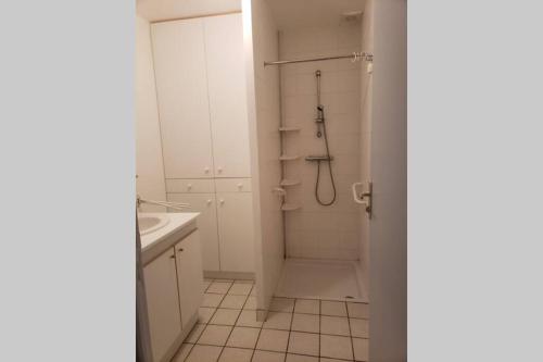 a white bathroom with a shower and a sink at Maison chaleureuse avec parking gratuit sur place in Saint-Romain-sur-Cher