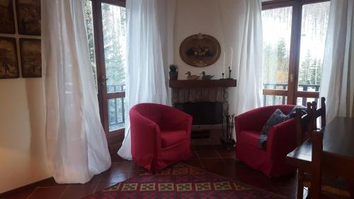 a living room with two red chairs and a fireplace at coeur de neige in Claviere