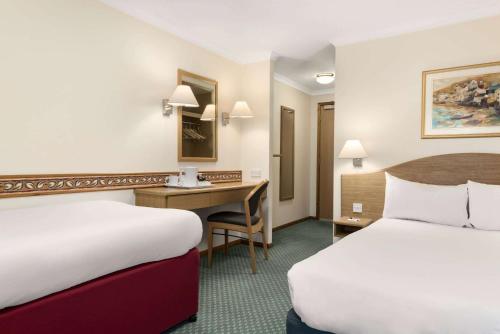 a hotel room with two beds and a desk at Days Inn by Wyndham Donington in Castle Donington