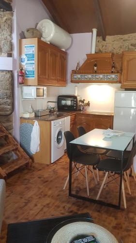 cocina con mesa y cocina con fogones y nevera en A Paragűeria, en Sas de Penelas
