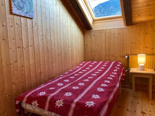a bedroom with a red bed in a room with a window at L'Arpille in Salvan