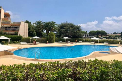 a large swimming pool with chairs and umbrellas at Appartement lumineux 6 places avec vue sur Marina in Mandelieu-la-Napoule