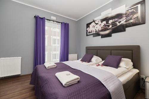 sypialnia z 2 łóżkami z fioletowymi zasłonami i telewizorem w obiekcie Apartments Wrocław Jana Pawła II with FREE PARKING Wrocław by Noclegi Renters we Wrocławiu