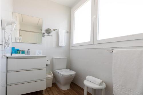 a white bathroom with a toilet and a window at Alcossebre Sea Experience in Alcossebre