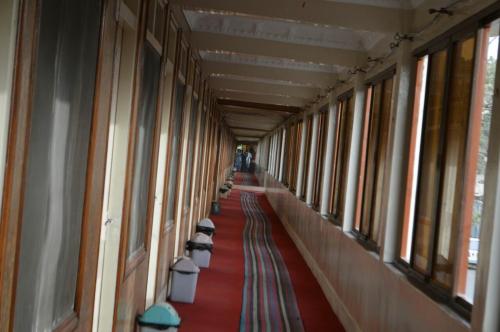 um corredor de um edifício com um tapete vermelho e janelas em Hotel Deluxe em Kachāhri