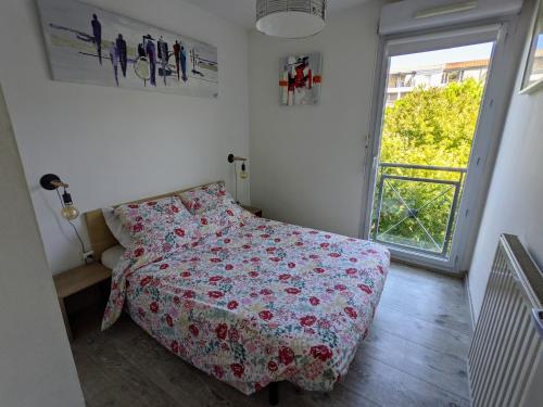 - une chambre avec un lit doté d'un couvre-lit floral et d'une fenêtre dans l'établissement F2 garage box WiFi terasse clim Gare Fac Eco Richter, à Montpellier