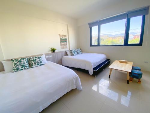 a bedroom with two beds and a table and a window at 這好宅 in Luodong