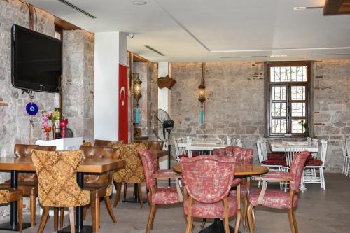 a dining room with tables and chairs and a flat screen tv at Orchis Hotel in Ayvalık