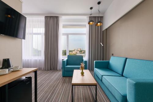 un soggiorno con 2 divani blu e un tavolo di Aerostar Hotel a Mosca