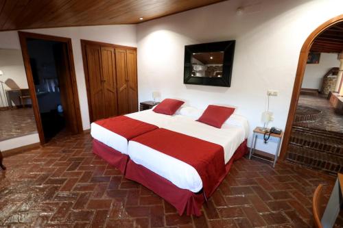 a bedroom with a large bed with red and white sheets at Hotel Monasterio de Rocamador in Almendral