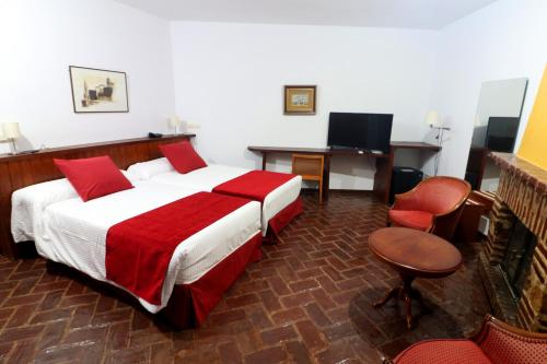 a bedroom with a large bed and a desk and a chair at Hotel Monasterio de Rocamador in Almendral