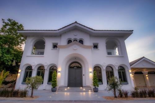a white house with a black door at Villa Malaga - Exclusive 5-Bedroom Villa with Signature Amenities By Luxury Explorers' Collection in Dubai