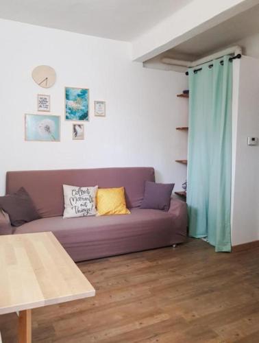 een woonkamer met een paarse bank en een tafel bij Studio Menta in centre, 4 minutes from the sea in Bordighera