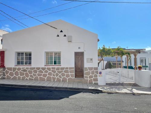 een wit huis op een straat met een hek bij La Casita de la Parra, El Hierro in Tamaduste