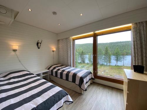 Cette chambre comprend deux lits et une grande fenêtre. dans l'établissement Scandi House Levi, à Levi