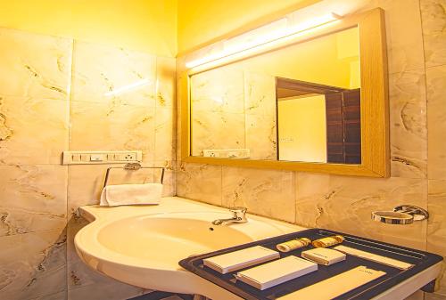 a bathroom with a sink and a mirror at Aron Resort Lonavala - Near Old Mumbai Pune Highway in Lonavala