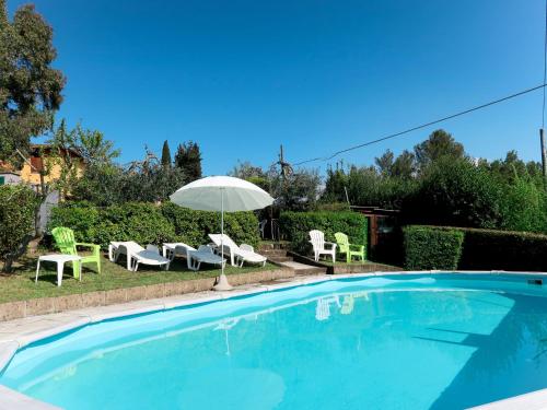 a swimming pool with an umbrella and chairs and a table and chairs at Apartment L'Uccelliera-3 by Interhome in Canneto