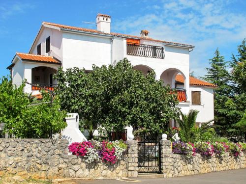 una casa blanca con flores en una pared de piedra en Apartment Dilly - KRK116 by Interhome en Pinezici