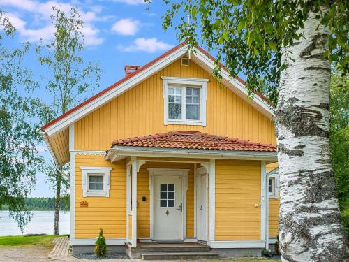 una casa amarilla con una puerta blanca y un árbol en Holiday Home Hintrekki by Interhome, en Kaustinen