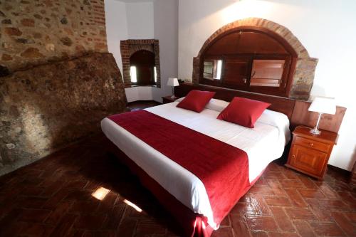 a bedroom with a large bed with red pillows at Hotel Monasterio de Rocamador in Almendral