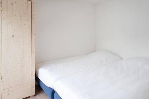 1 dormitorio con cama blanca y armario de madera en klaproos, en Bergen