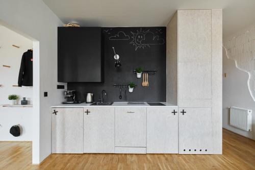 uma cozinha com armários brancos e uma parede preta em Cozy Flat in New Town by Prague Days em Praga
